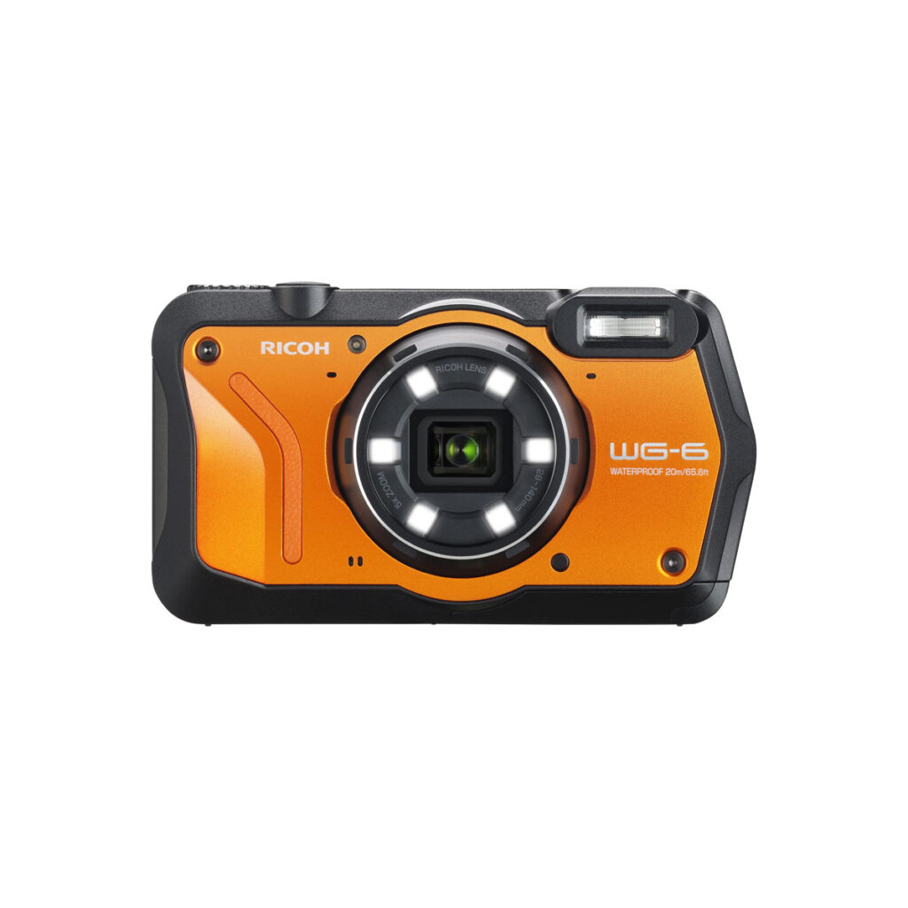 Ricoh_WG-6_005 Etukuva Ricoh WG-6 Orange Kompaktikamerasta valkoisella pohjalla, jossa korostuu objektiivi ja sitä ympäröivät LED-valot, salama ja ohjauspainikkeet.