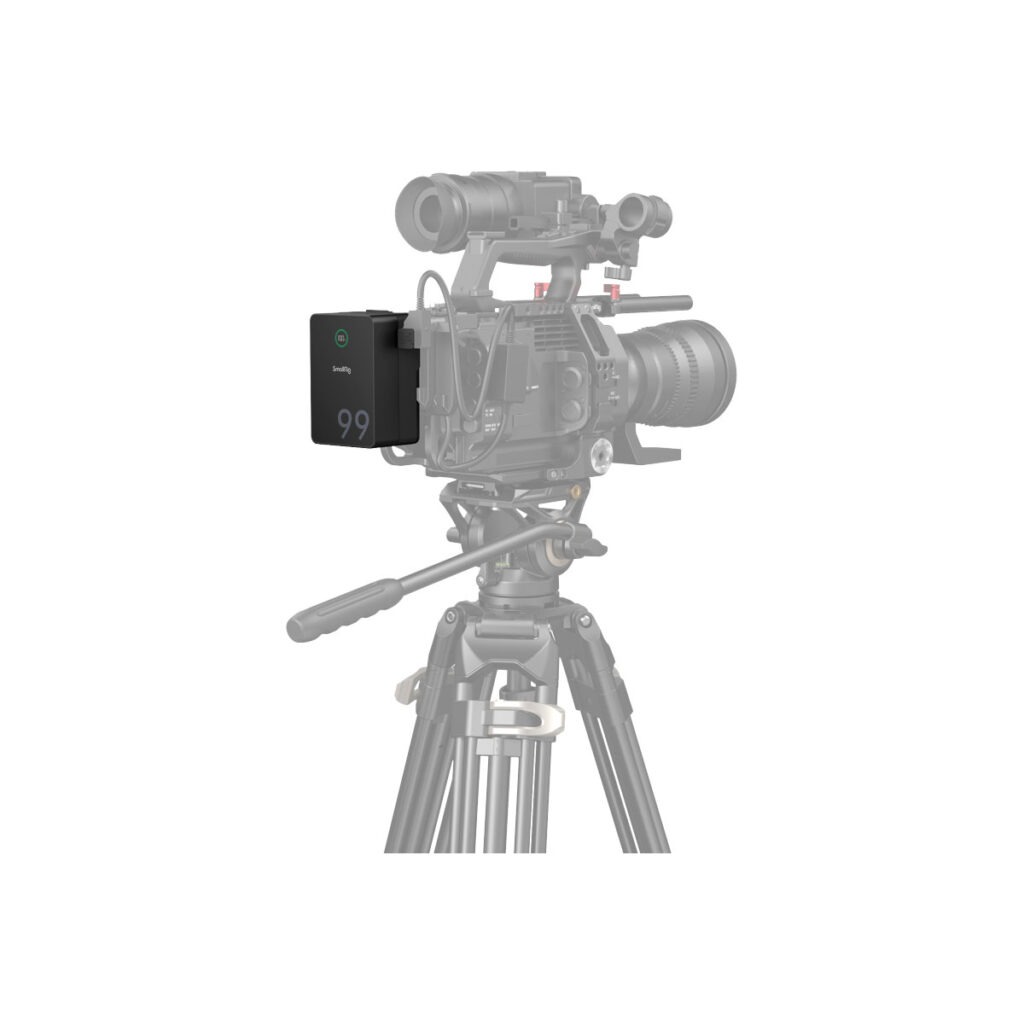 SmallRig_4292_006 Close-up of a professional video camera on a tripod with a SmallRig 4292 VB99 Pro mini V-Mount battery attached to the side. The camera and tripod appear partially faded.