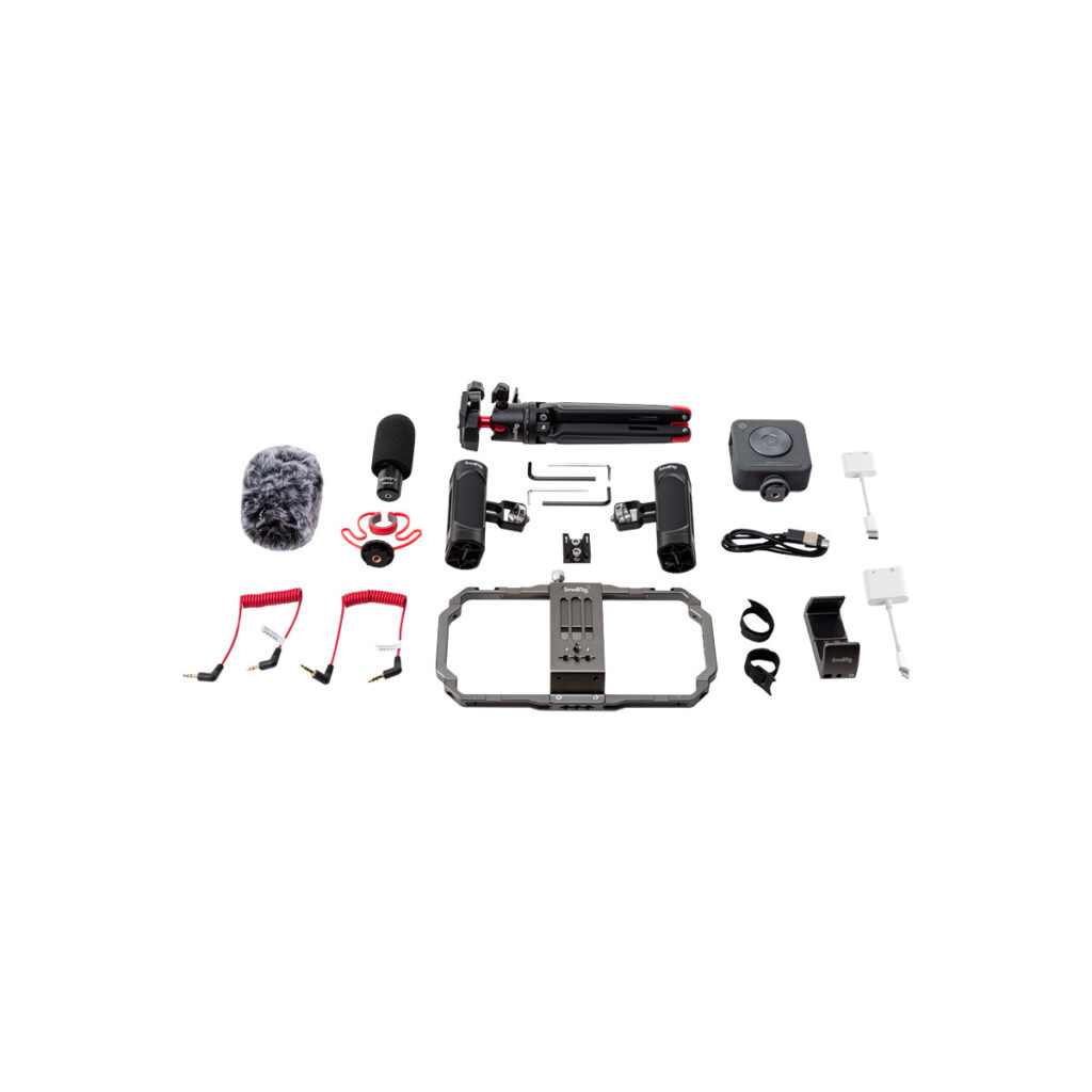 Smallrig_3384_003 SmallRig 3384 Professional Vlogging Kitin litteä ulkoasu, jossa on mikrofoni tuulisuojalla, kolmijalka, älypuhelinlaite, kaapelit, kiinnikkeet, adapterit ja muut audio-videovälineet siististi järjestettyinä valkoiselle taustalle.