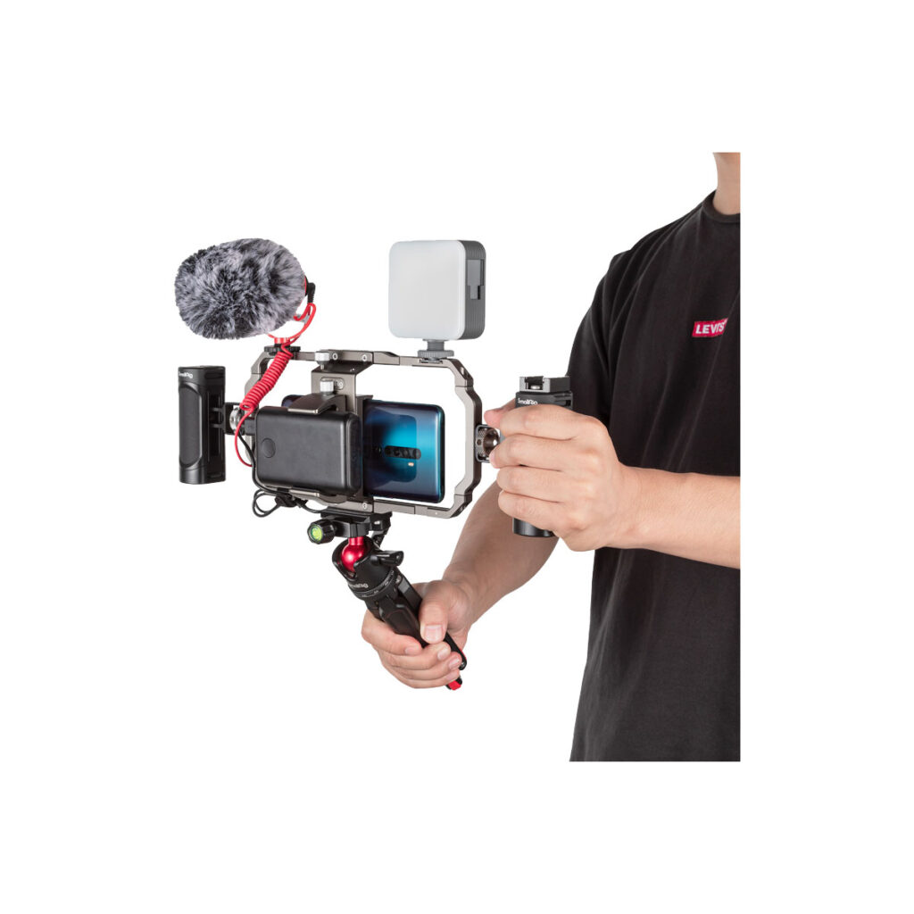 Smallrig_3384_004 Henkilö käyttää SmallRig 3384 Professional Vlogging Kit -laitteistoa, jossa on älypuhelin, johon on asennettu mikrofoni, LED-valo ja kahva - täydellinen vloggaamiseen tai kuvaamiseen tien päällä.