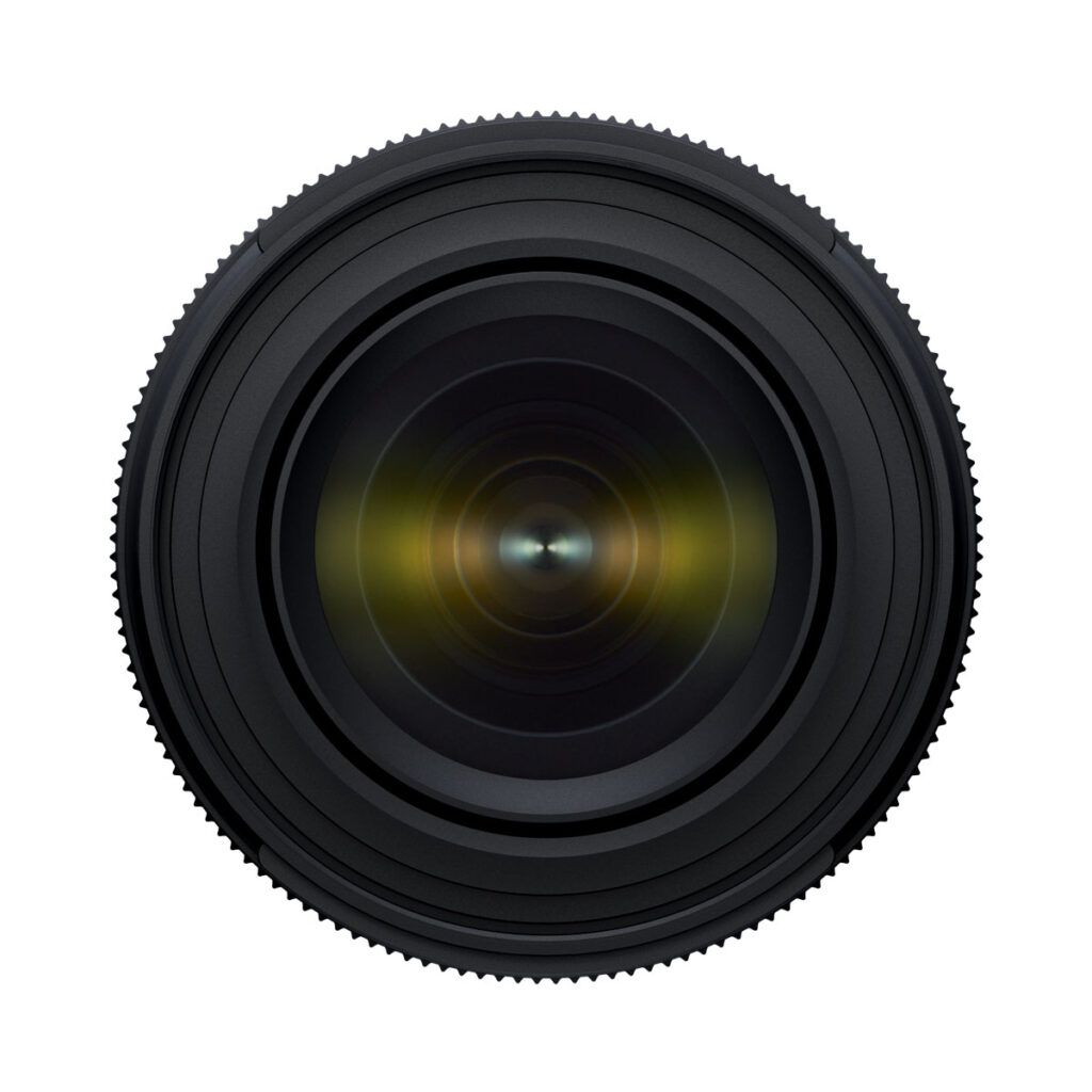 Tamron_17-50_f4_004 Close-up of the Tamron 17-50mm F/4 Di III VXD lens for the Sony E, with the lens facing forwards, showing concentric rings and reflected glass elements against a white background.