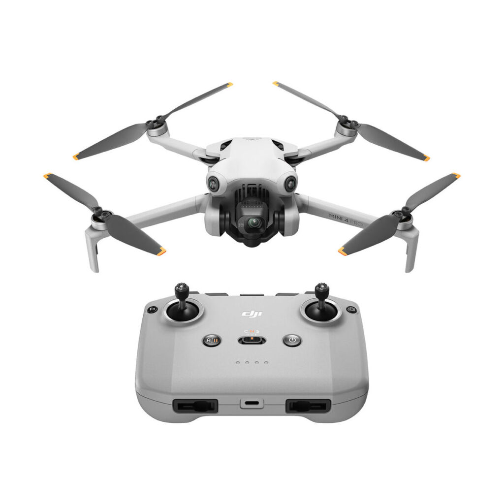 mini_4_pro_rc-n2_01 Harmaa DJI Mini 4 Pro -lennokki, jossa on neljä potkuria ja kamera, on kuvattu sopivan harmaan kauko-ohjaimen yläpuolella, jossa on kaksi joystickiä ja useita painikkeita valkoisella pohjalla.