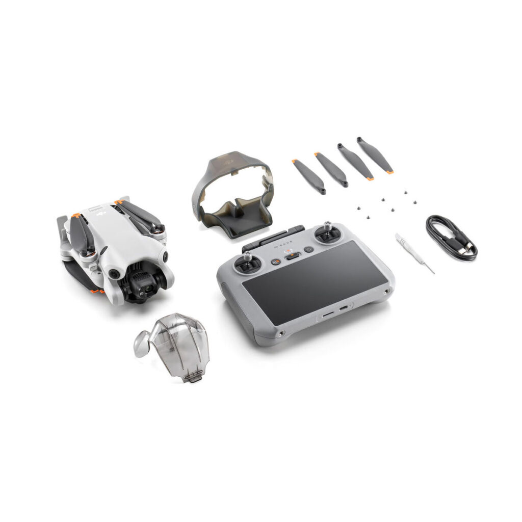 mini_4_pro_rc2_01 DJI Mini 4 Pro RC2 ohjain -lennokkipakkaus sisältää kokoontaitetun lennokin, kauko-ohjaimen, kaksi suojakuorta, neljä varapotkurin lavaa, ruuvit, ruuvimeisselin ja USB-kaapelin, jotka on järjestetty siististi valkoiselle taustalle.
