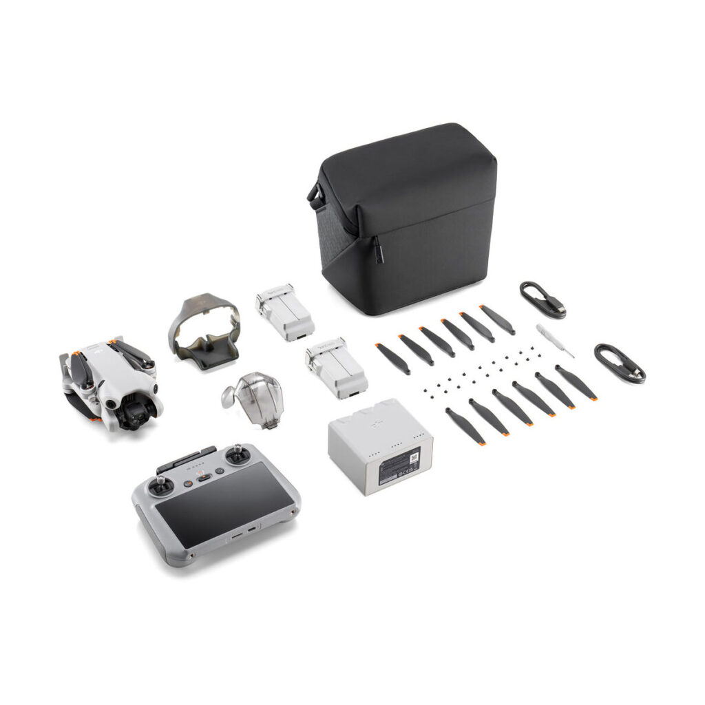 mini_4_pro_rc2_flymore_01 DJI Mini 4 Pro Fly More Combo + RC2 ohjain -lennokkisarja sisältää lennokin, ohjaimen, kaksi akkua, laturin, potkurit, kaapelit, varaosat, lisävarusteet ja mustan kantolaukun - kaikki siististi esillä valkoisella pohjalla.