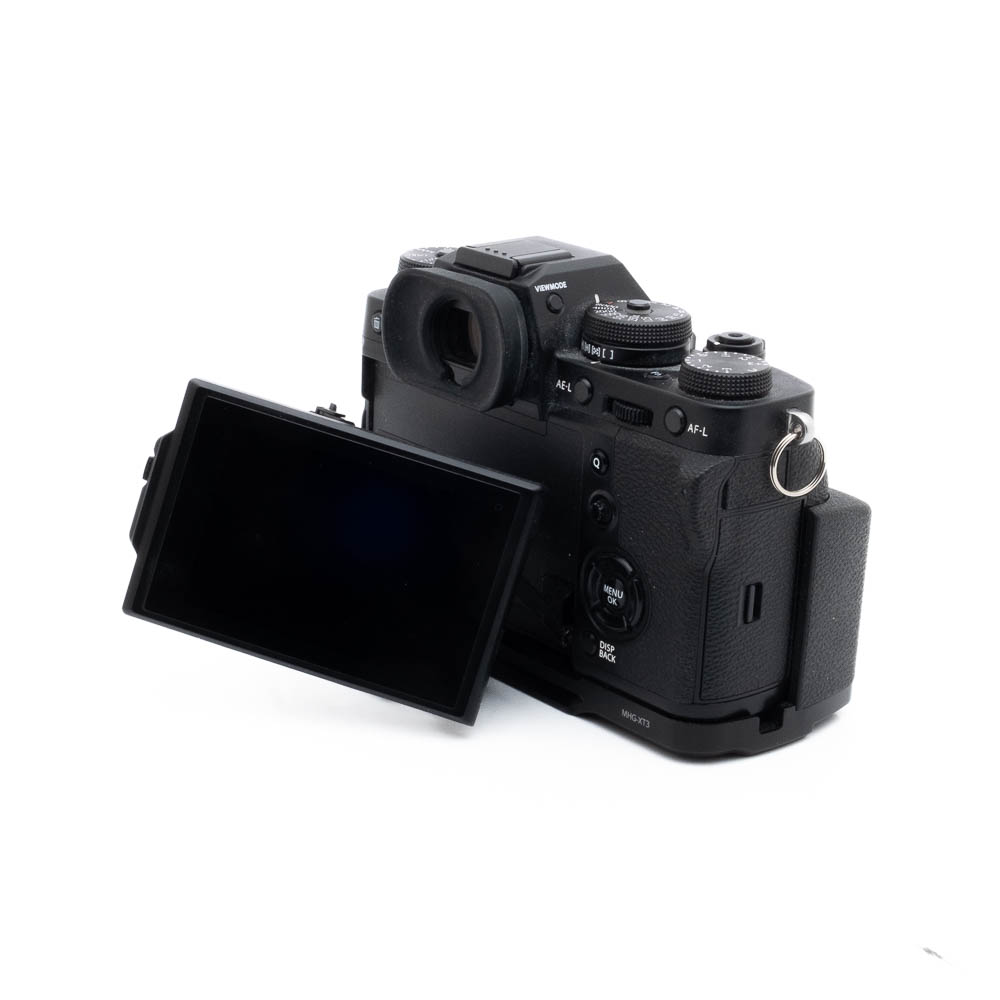 Fuji X-T3 + kahva-3 Fujinon GF 50mm f/3.5 R LM WR (sis.ALV24%) - Käytetty -objektiivi on kuvassa kiinnitettynä mustaan digitaalikameraan takaa katsottuna, LCD-näyttö on käännetty ulos ja ohjauspainikkeet näkyvät rungossa.