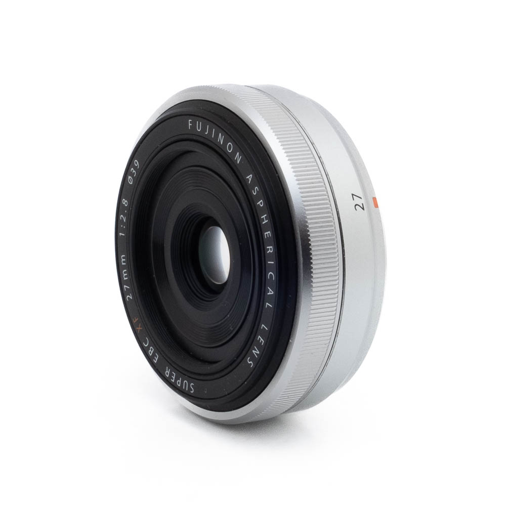 Fujinon 27mm f28-2 Hopeinen Fujinon GF 50mm f/3.5 R LM WR (sis.ALV24%) - Käytetty -objektiivi seisoo pystyssä valkoisella taustalla. Kompaktissa ja tyylikkäässä objektiivissa on mustia ja hopeisia yksityiskohtia ja etuelementtiä ympäröivä kaiverrettu teksti.