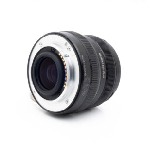 Fujinon 35mm f2 R WR-1 Fujinon GF 50mm f/3.5 R LM WR (sis.ALV24%) - Käytetty objektiivi, musta, hopeisella metallikiinnityksellä, lepää valkoisella pinnalla, joka on käännetty taaksepäin, jotta elektroniset kontaktit ja säänkestävyysmerkintä tulevat esiin.