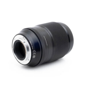 Fujinon 90mm f2 R LM WR-1-2 Fujinon GF 50mm f/3.5 R LM WR (sis.ALV24%) - Käytetty musta kameraobjektiivi on näytetty kyljellään valkoista taustaa vasten, ja siinä näkyy metallinen objektiivin kiinnitys ja elektroniset kontaktit.