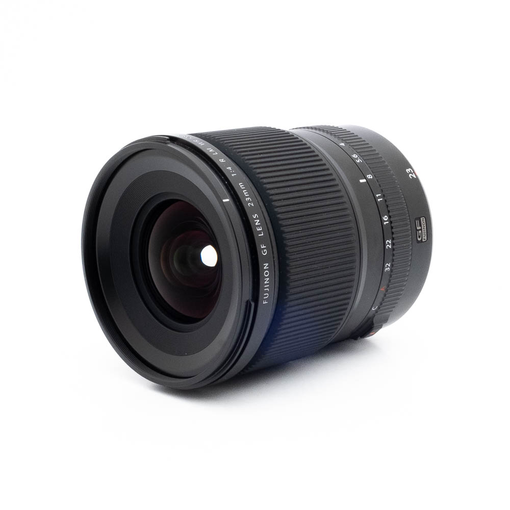 Fujinon GF 23mm f4 R LM WR-2 Fujinon GF 50mm f/3.5 R LM WR (sis.ALV24%) - Käytetty kameraobjektiivi, jossa on uurrettu tarkennusrengas, on sijoitettu valkoiselle taustalle, ja siinä näkyy etulasielementti ja objektiivin merkinnät.
