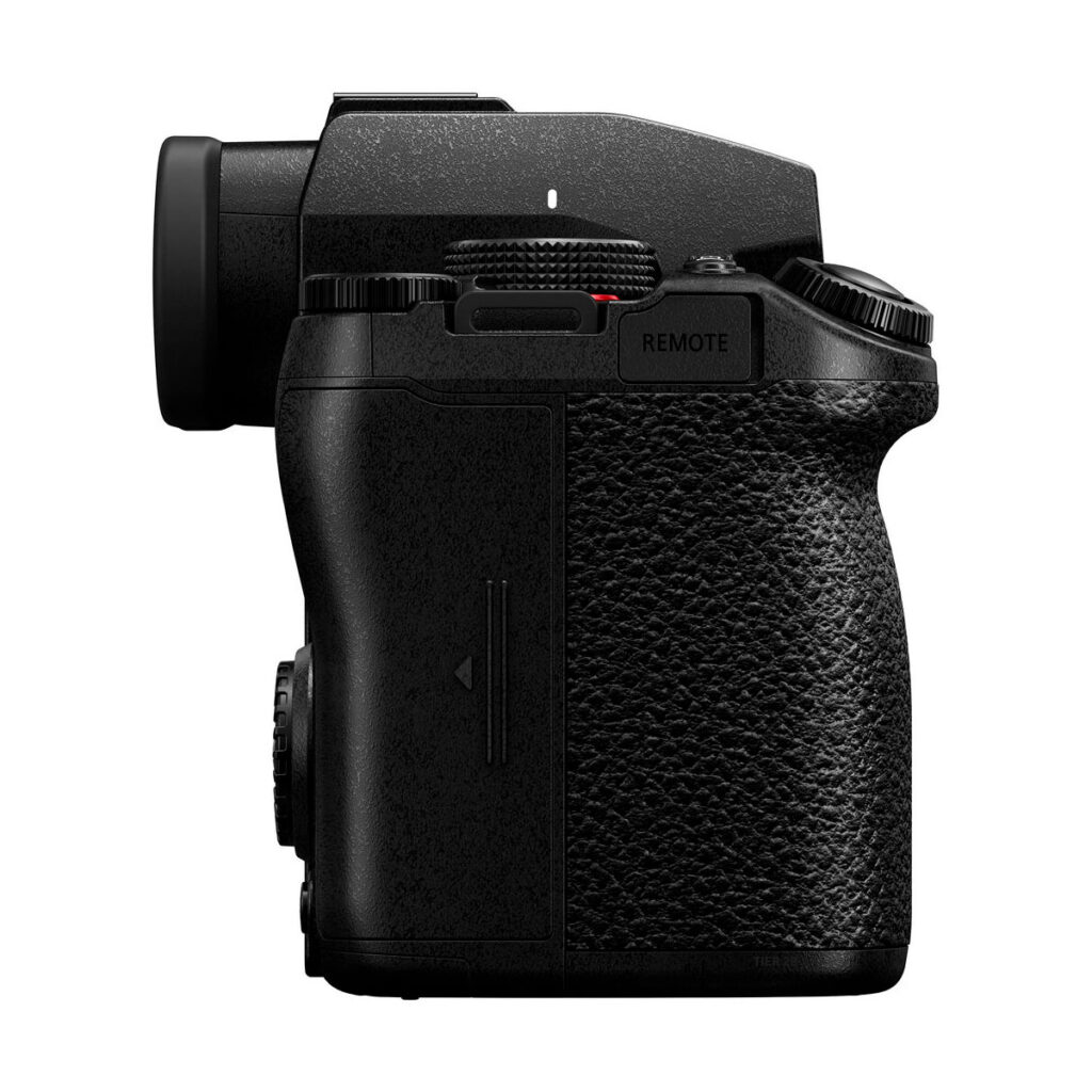 Lumix_G9II_005 Sivukuva Panasonic Lumix G9 II -järjestelmäkameran mustasta rungosta, jossa on kuvioitu kahva, elektroninen etsin ja useita valintakiekkoja ja painikkeita, kuvattuna valkoista taustaa vasten.