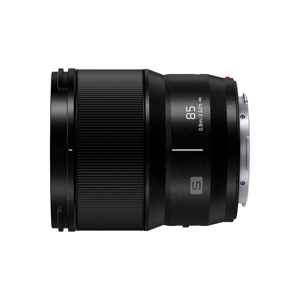 Lumix_S_85mm_002 Panasonic Lumix S 85mm f/1.8 -objektiivi näkyy sivuprofiilissa valkoista taustaa vasten, ja siinä on mustat kuvioidut ja sileät osat, 85 ja 0.80m/2.62ft -merkinnät sekä metallinen kiinnitysrengas.