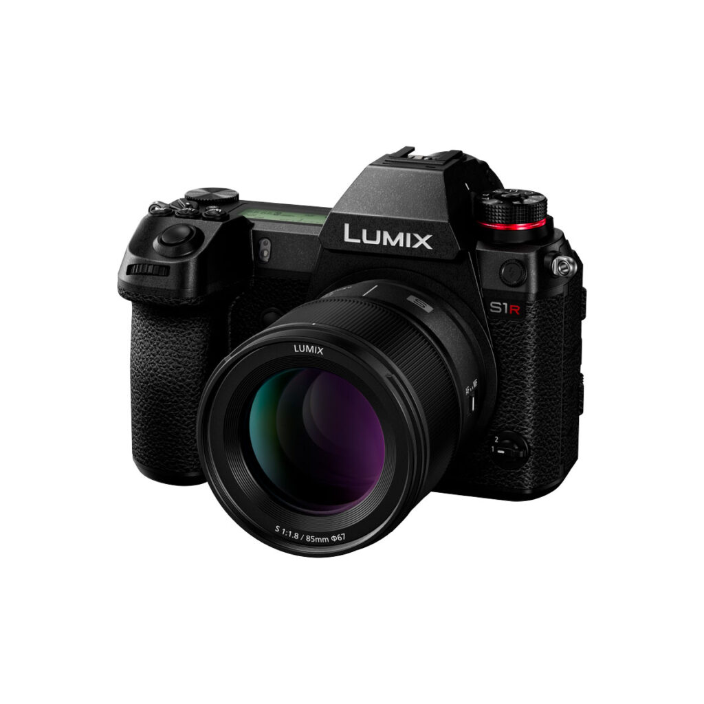 Lumix_S_85mm_004 Musta Panasonic Lumix S1R peilitön digitaalikamera, johon on kiinnitetty Panasonic Lumix S 85mm f/1.8 -objektiivi, kuvattu valkoisella taustalla.