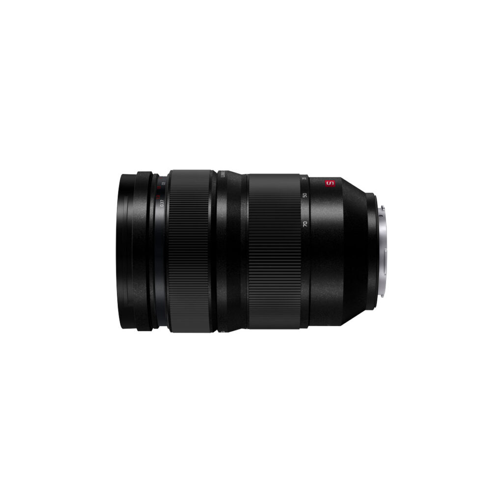 Lumix_S_PRO_27-70mm_004 Panasonic Lumix S Pro 24-70mm f/2.8 -objektiivi on kompakti, sylinterimäinen musta vaihdettava kameran objektiivi, jossa on zoomaus- ja tarkennusrenkaat, metallinen kiinnitys, ja se on kuvattu sivulta valkoista taustaa vasten.