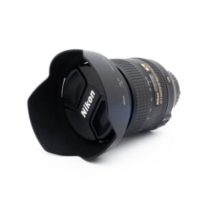 Nikon 24-120mm f4 G ED VR-3 Fujinon GF 50mm f/3.5 R LM WR (sis.ALV24%) - Käytetty objektiivi, jossa on vastavalosuoja ja suojus, on sijoitettu valkoiselle taustalle, jossa näkyy erilaisia merkintöjä ja tarroja.
