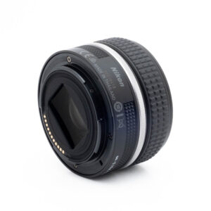 Nikon Z 28mm f28-1-2 Fujinon GF 50mm f/3.5 R LM WR (sis.ALV24%) - Käytetty -objektiivi kuvakulmasta katsottuna, jossa korostuvat takakiinnitys elektronisilla koskettimilla, kuvioitu tarkennusrengas ja tuoteseloste, kaikki valkoista taustaa vasten.