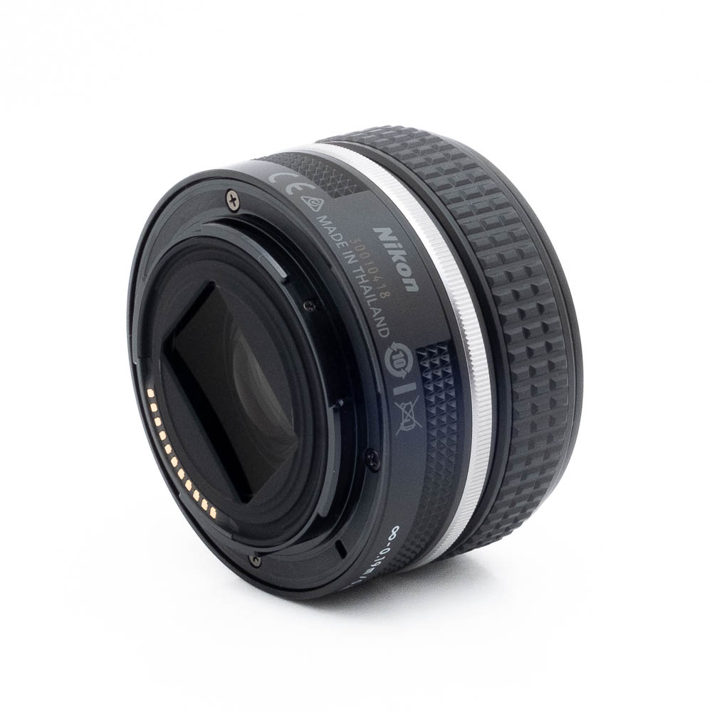 Nikon Z 28mm f28-1-2 Fujinon GF 50mm f/3.5 R LM WR (sis.ALV24%) - Käytetty -objektiivi kuvakulmasta katsottuna, jossa korostuvat takakiinnitys elektronisilla koskettimilla, kuvioitu tarkennusrengas ja tuoteseloste, kaikki valkoista taustaa vasten.
