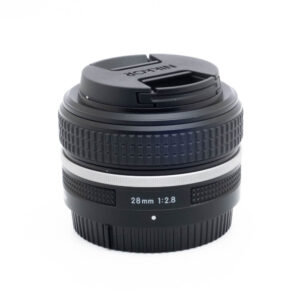 Nikon Z 28mm f28-3-2 Fujinon GF 50mm f/3.5 R LM WR -objektiivi (sis.ALV24%) - Käytetty, jossa on tyylikäs musta muotoilu ja kiinnitetty objektiivin suojus valkoisella pohjalla.
