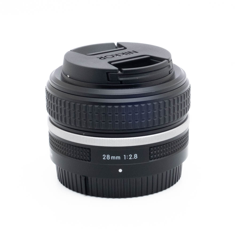 Nikon Z 28mm f28-3-2 Fujinon GF 50mm f/3.5 R LM WR -objektiivi (sis.ALV24%) - Käytetty, jossa on tyylikäs musta muotoilu ja kiinnitetty objektiivin suojus valkoisella pohjalla.