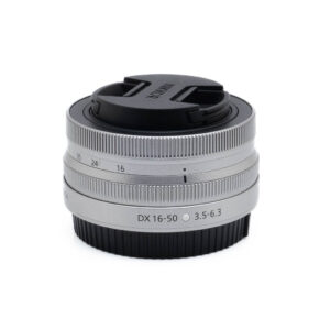 Nikon Z DX 16-50mm f35-63-3-2 Fujinon GF 50mm f/3.5 R LM WR (sis.ALV24%) - Käytetty kameran objektiivi, johon on kiinnitetty musta objektiivin suojus, valkoista taustaa vasten.
