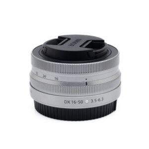 Nikon Z DX 16-50mm f35-63-3-2 Fujinon GF 50mm f/3.5 R LM WR (sis.ALV24%) - Käytetty kameran objektiivi, johon on kiinnitetty musta objektiivin suojus, valkoista taustaa vasten.