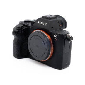 Fujinon GF 50mm f/3.5 R LM WR (sis.ALV24%) - Käytetty -objektiivi, jonka suojus on kiinni, hieman vinossa valkoista taustaa vasten.