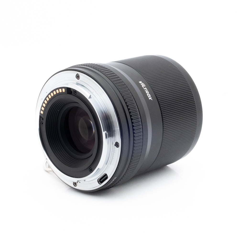 Viltrox AF 33mm f14 Z-1 Lähikuva Fujinon GF 50mm f/3.5 R LM WR (sis.ALV24%) - Käytetty -objektiivista kyljellään, jossa näkyy takakiinnitys, elektroniset koskettimet ja uurrettu tarkennusrengas valkoista taustaa vasten.