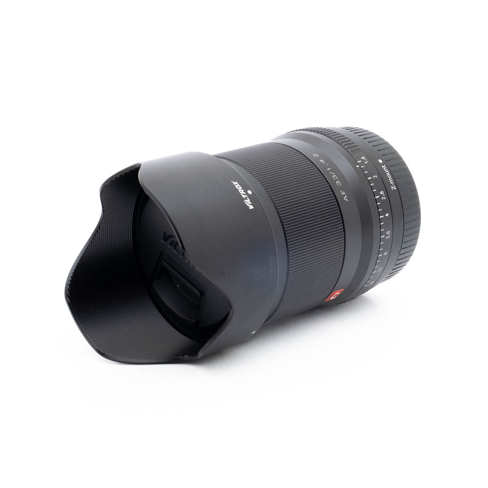 Viltrox AF 33mm f14 Z-3 Fujinon GF 50mm f/3.5 R LM WR (sis.ALV24%) - Käytetty objektiivi, jossa on suuri terälehden muotoinen huppu, vasemmalle suunnattu kuvakulma valkoisella taustalla. Tarkennus- ja zoomausrenkaat, joihin on merkitty numerot, ovat näkyvissä.