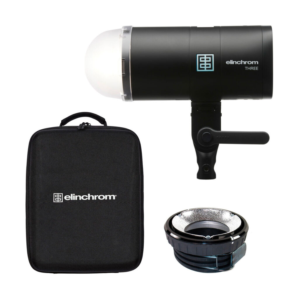 elinchrom_three_04 Elinchrom THREE -studiovalaisin mustana, kuvassa kupolidiffuusori, pyöreä hopeinen heijastin ja yhteensopiva musta kantolaukku valkoisella pohjalla.
