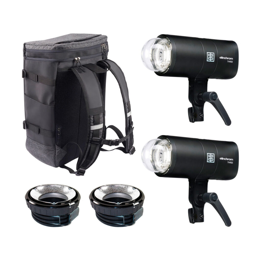 elinchrom_three_dual_01 Elinchrom THREE Dual -pakkaus sisältää kaksi mustaa studiosalamalaitetta, kaksi pientä hopeista heijastinta sekä harmaan ja mustan repun, jotka kaikki ovat esillä valkoisella pohjalla.