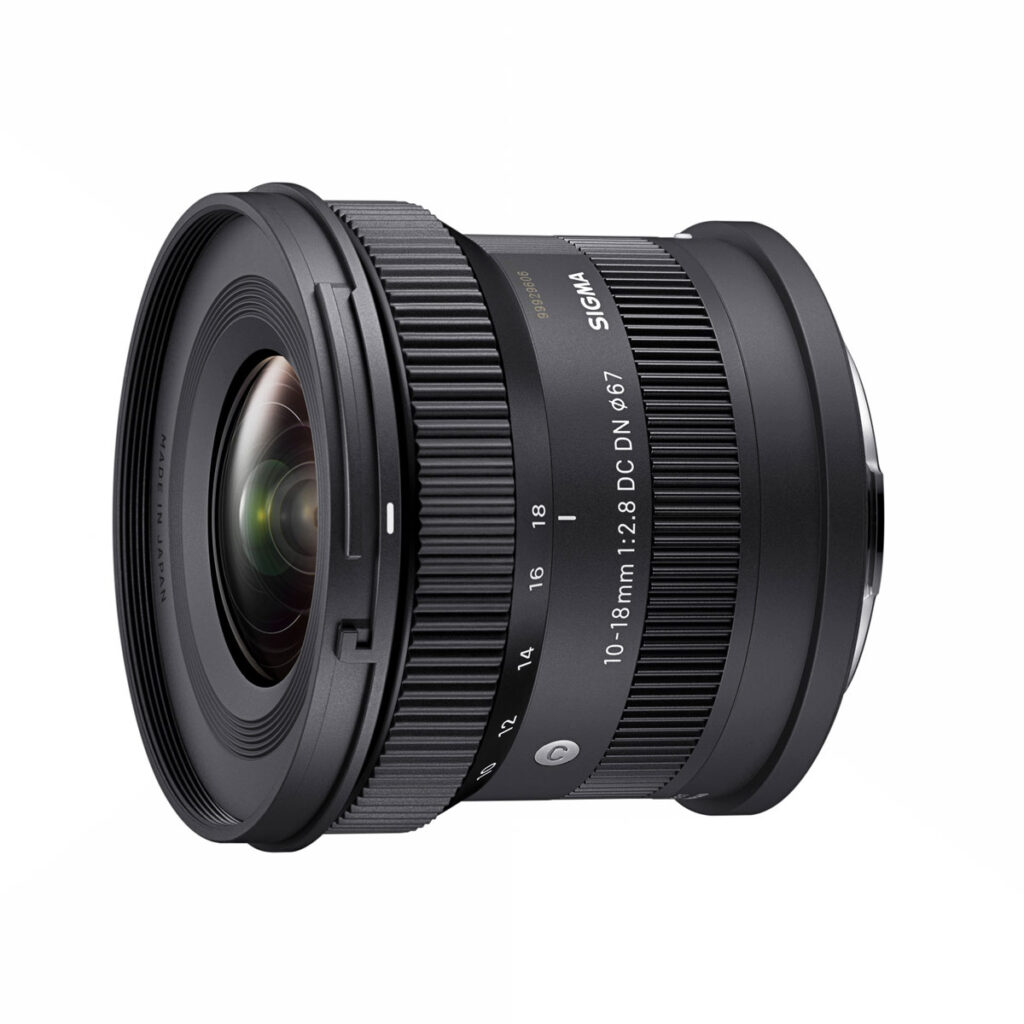 sigma_10-18mm_f28_02 Sigma 10-18mm f/2.8 DC DN -objektiivi, Sony E on kuvattu valkoisella taustalla, jolloin sen laaja zoomausrengas, yksityiskohtaiset linssimerkinnät ja lasinen etuelementti korostuvat.