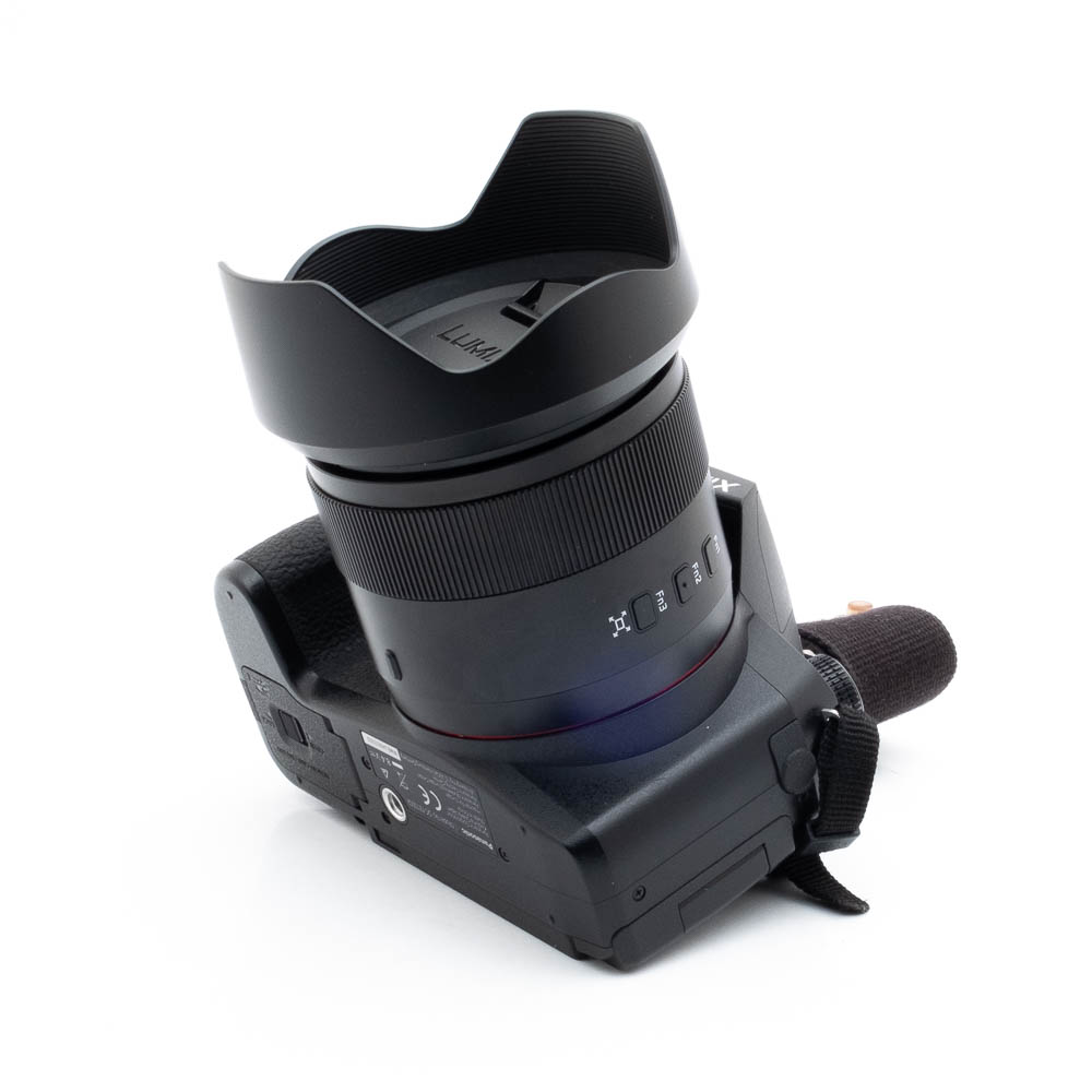 Lumix -1 Nikon Nikkor Z MC 105mm f/2.8 VR S (Kunto K5) - Käytetty on kuvattu kulmassa valkoisella taustalla, ja siinä on suuri vastavalosuoja, kuvioitu kahva, ohjauspainikkeet ja hihna.