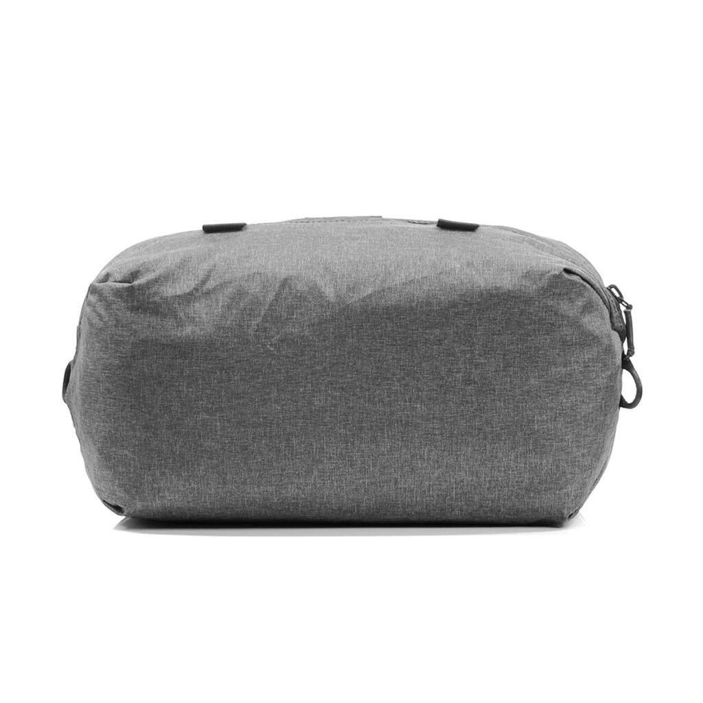 Peak-Design-Shoe-Pouch---Charcoal1 Peak Design Shoe Pouch in Charcoal näkyy alhaalta, ja siinä on sileä, litteä pohja, jossa on pyöristetyt reunat ja kaksi pientä mustaa silmukkaa yläosassa.