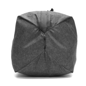 Peak-Design-Shoe-Pouch---Charcoal2 Peak Design Shoe Pouch - Charcoal on harmaa, kankainen matkapussi, jossa on näkyvä vetoketju ylhäällä ja joka näkyy sivulta, jossa on rakenteellinen geometrinen muoto valkoista taustaa vasten.