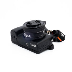 Sony A6400-1 Nikon Nikkor Z MC 105mm f/2.8 VR S (Kunto K5) - Käytetty objektiivi, johon on kiinnitetty suojus, näkyy valkoisella pinnalla, ja siinä on musta käsihihna, jonka oikealla puolella näkyy oransseja korostuksia.