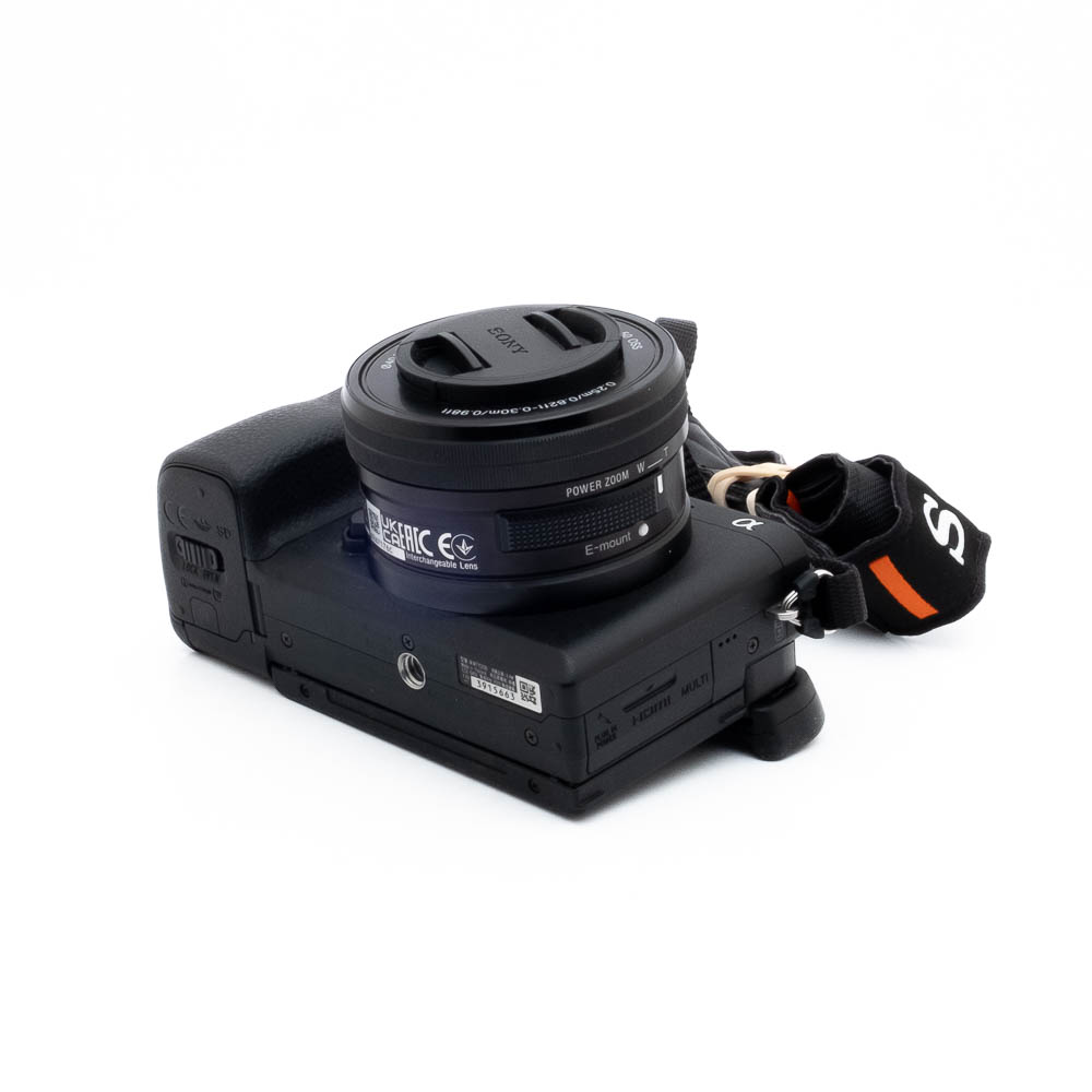 Sony A6400-1 Nikon Nikkor Z MC 105mm f/2.8 VR S (Kunto K5) - Käytetty objektiivi, johon on kiinnitetty suojus, näkyy valkoisella pinnalla, ja siinä on musta käsihihna, jonka oikealla puolella näkyy oransseja korostuksia.