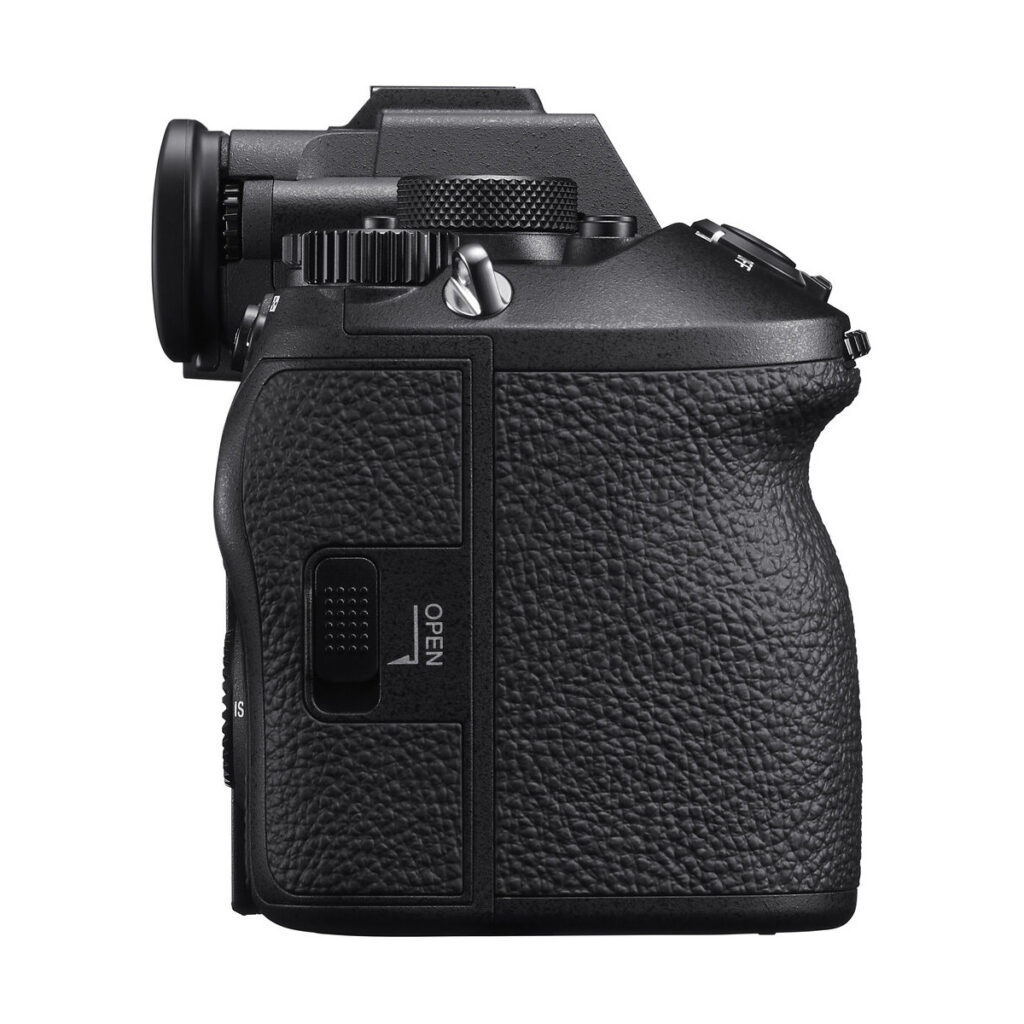 sony_a9_iii_03 Sivukuva mustasta Sony A9 III -järjestelmäkamerasta, jossa on kuvioitu kahva, etsin, ohjauspainikkeet ja OPEN-merkitty lokero, eristettynä valkoiselle taustalle.