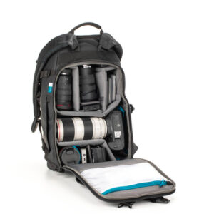 tenba_axis_20l_camo_01 The Tenba Axis v2 20L Backpack MultiCammusta in black shows the main compartment open, with camera gear organized - lenses, camera body, flash and accessories in padded compartments - and a zippered pocket on the front flap.