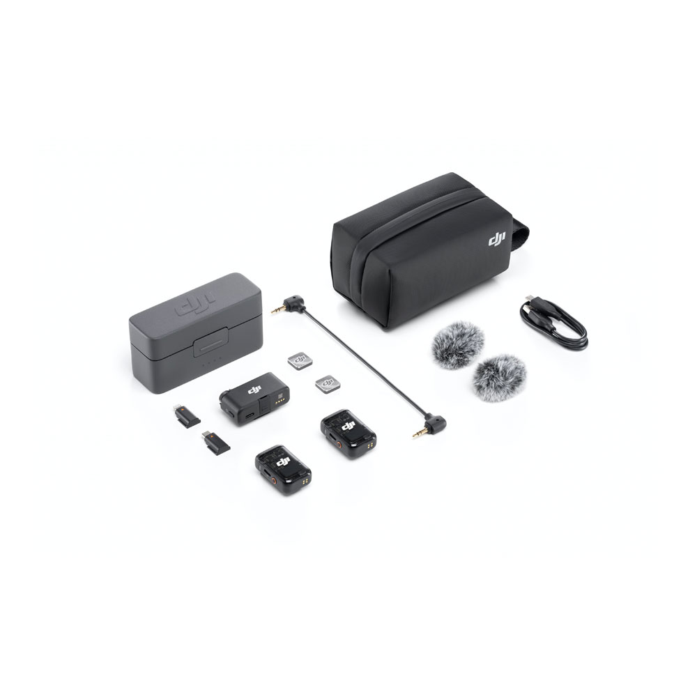 DJI_Mic2_1+2_007 DJI Mic 2 Dual Kit -langaton mikrofonijärjestelmä näkyy valkoisella pinnalla, jossa on kaksi lähetintä, yksi vastaanotin, latauskotelo, kaksi karvaista tuulilasia, USB-kaapelit, sovitinkaapelit, microSD-kortit ja musta kantolaukku.