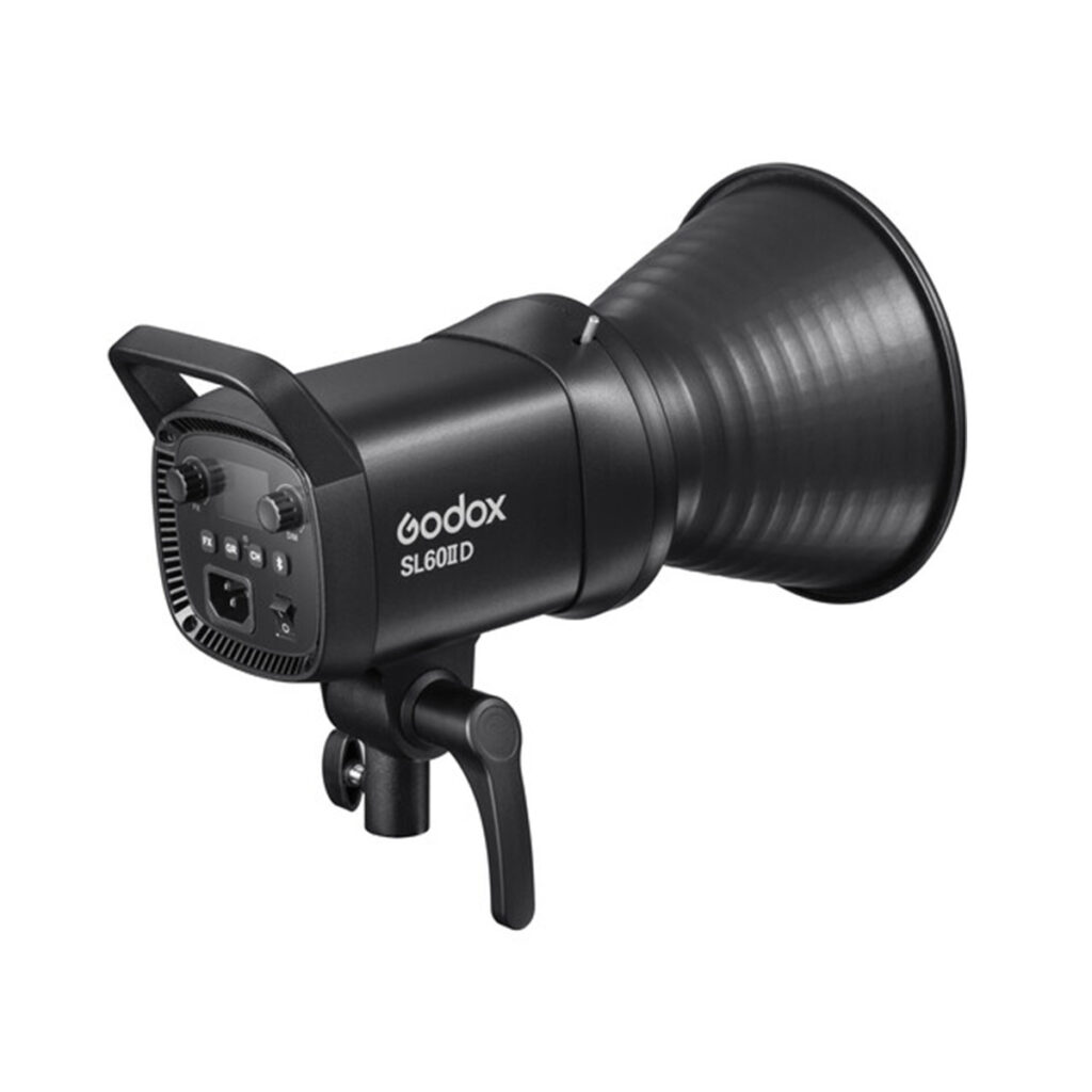 Godox SL60IID4 Godox SL60IID LED-videovalaisin -LED-valo mustana on kuvassa kulmikkaasti käännettynä, jotta sen takaosan säätimet ja etuosan heijastin tulevat näkyviin, ja kiinnityskahva on näkyvissä.
