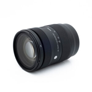 Sigma 28-70mm f/2.8 DG DN C L-Mount - Käytetty on kuvattu kulmassa valkoisella taustalla, ja kuvassa näkyvät musta runko, tarkennusrengas, zoomausrengas, polttovälimerkinnät (28-70mm) ja tuotemerkin merkintä.