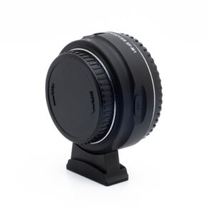 Viltrox EF-M1 Adapteri - Käytetty, musta ja suojakorkki, on esillä pienellä jalustalla valkoista taustaa vasten. Adapterissa on USB-portti ja kohdistuksen ilmaisimet.