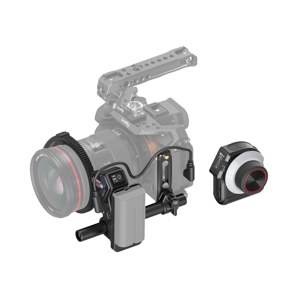 smallrig-3781-01 SmallRig 3781 MagicFIZ Wireless Follow Focus Basic Kit on kuvassa asennettuna ammattilaiskameraan, jossa on suuri objektiivi, ulkoinen akku ja kiinnitetty seurantatarkennus; sen langaton ohjausyksikkö on erikseen oikealla valkoista taustaa vasten.