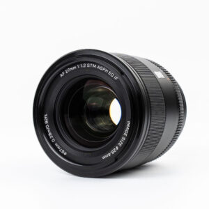 Lähikuvassa mustasta Viltrox AF PRO 27mm f/1.2 -objektiivi, Fuji X -objektiivista näkyvät sen lasielementit ja yksityiskohtainen teksti AF 27mm 1:1.2 STM ASPH ED IF, joka korostaa teknisiä tietoja valkoista taustaa vasten.