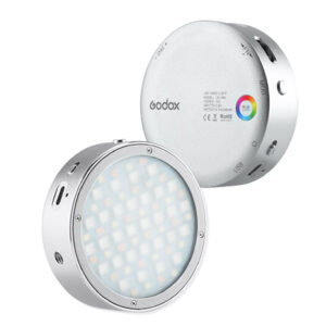 1578299547_903 Godox R1 + AK R1 -sarjassa on kaksi pyöreää, hopeista LED-videovalaisinta - toisessa näkyy etupuolen LED-verkko ja toisessa takapuoli, jossa on ohjauspainikkeet, väripyörä ja useita portteja.