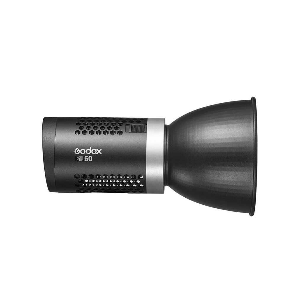 1600692413_416 Godox ML60 LED-valaisimen sivukuva esittelee sen lieriömäisen mustan rungon, jossa on tuuletusreikiä ja etupuolelle kiinnitetty kartionmuotoinen heijastin.