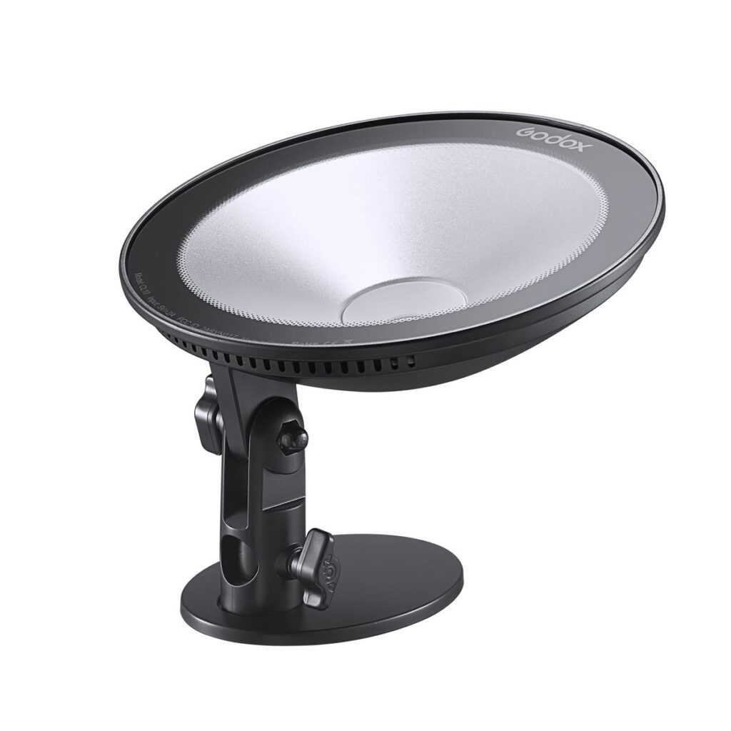 1609842607_439 Mustan ja hopeanvärinen Godox CL10 Ambient LED -valaisin, jossa on kaareva, pyöreä muotoilu, on asennettu säädettävään jalustaan valkoista taustaa vasten.