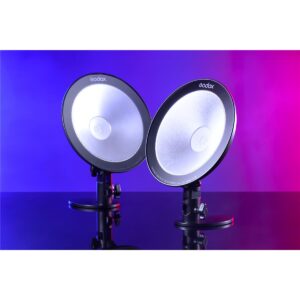 1609842609_182 Kaksi Godox CL10 Ambient LED -valaisinta on sijoitettu vierekkäin jalustalle, ja ne hehkuvat sinistä ja vaaleanpunaista sävyä, ja niiden valo heijastuu kiiltävästä pinnasta.