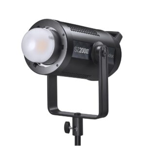 1611305677_723 Godox SZ200Bi zoomattava kaksivärinen LED-videovalaisin (LED-valo), musta, pyöristetyllä diffuusorilla, asennettu säädettävään jalustaan, hieman vasemmalle kallistettuna valkoista taustaa vasten.