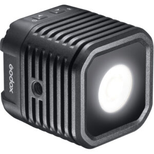 1617973841_400 Godox WL4B Waterproof LED-valaisin on kompakti, musta, neliön muotoinen LED, jossa on kirkas pyöreä keskus, lämpöä haihduttavat kyljet ja ohjauspainikkeet yläosassa.