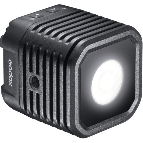 1617973841_400 Godox WL4B Waterproof LED-valaisin on kompakti, musta, neliön muotoinen LED, jossa on kirkas pyöreä keskus, lämpöä haihduttavat kyljet ja ohjauspainikkeet yläosassa.